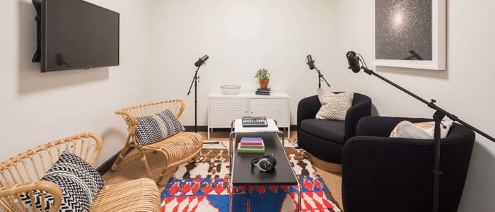 A room decorated with a colorful carpet and wicker sofas along with podcast microphones